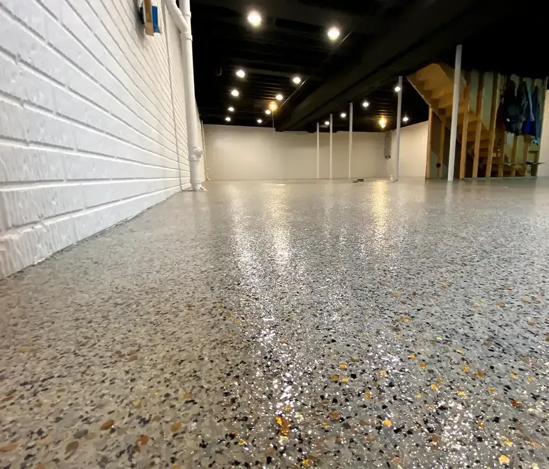 Basement floor in grey and amber flake running to a painted block wall