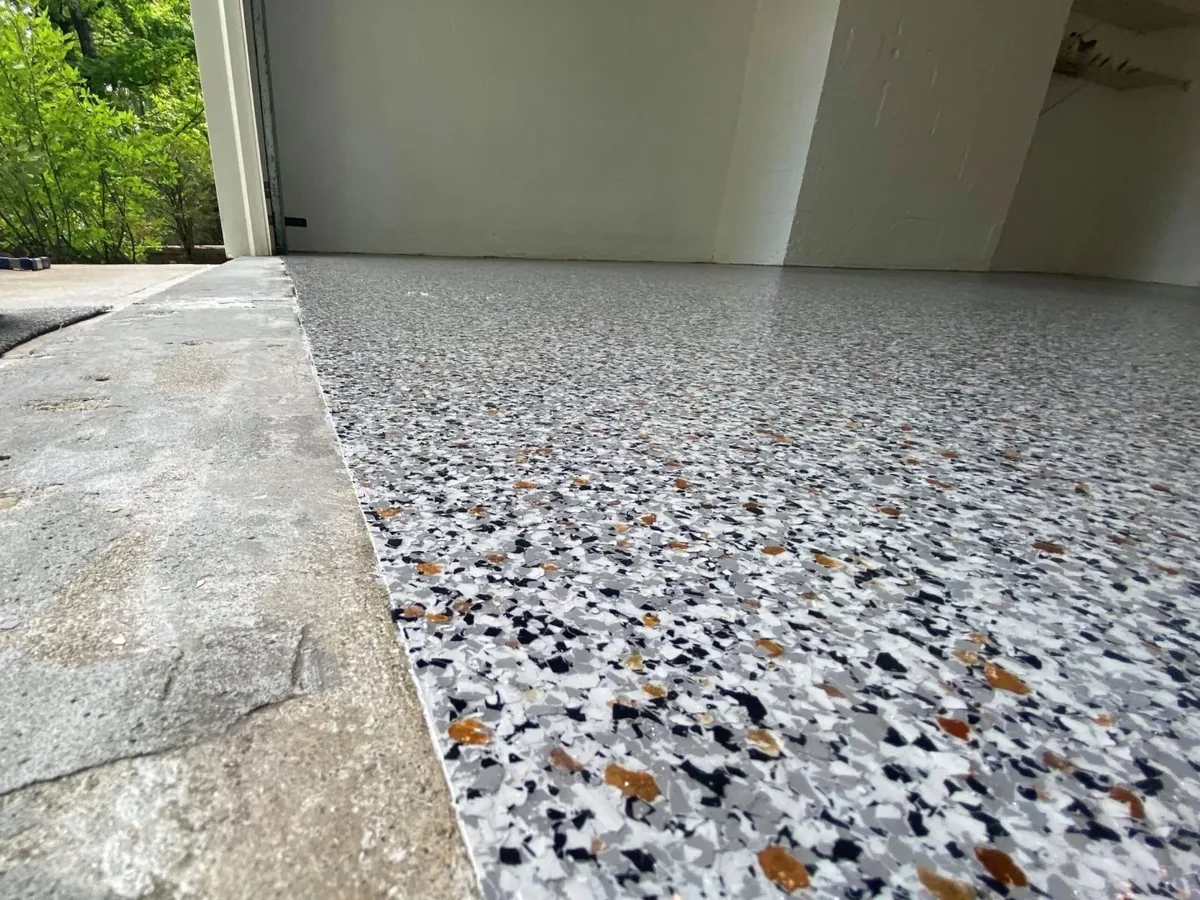 Bright garage floor in white, grey and amber flake with the door open to the yard