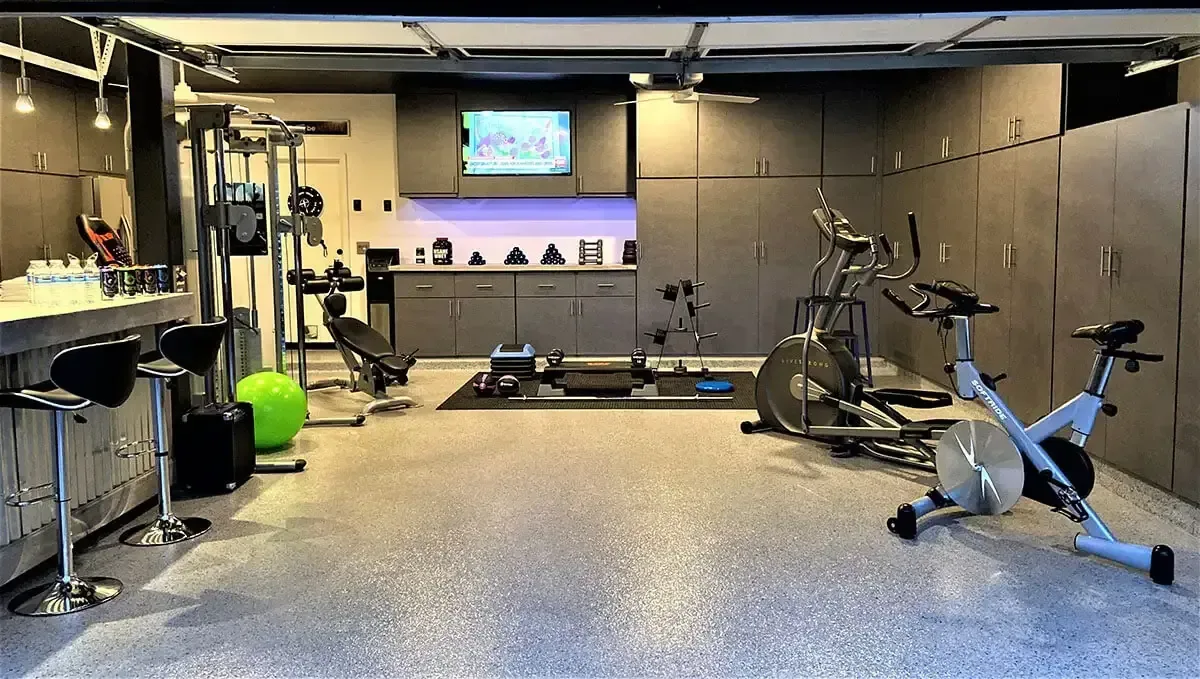 Garage converted to a home gym with a grey flake floor